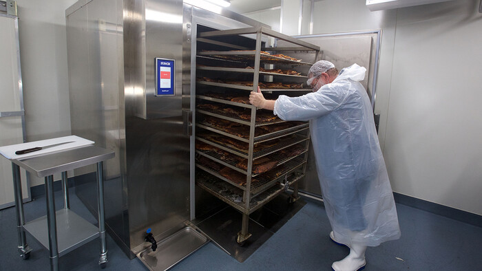 Removing the smoked meat from the meat smoker at Texas BBQ Foods